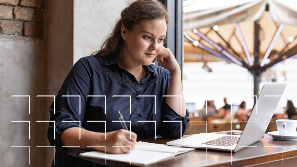 A young woman sitting and using her laptop in a coffee shop