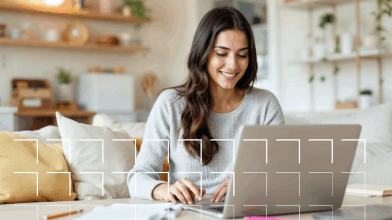 Smiling woman using a laptop at a desk in a cozy, modern living room with plants and shelves in the background.