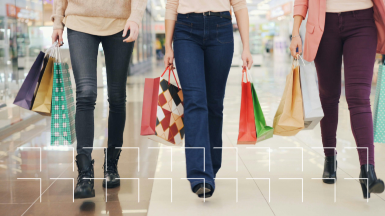 Three shoppers carrying shopping bags walk through a retail store, representing retail foot traffic driven by local visibility